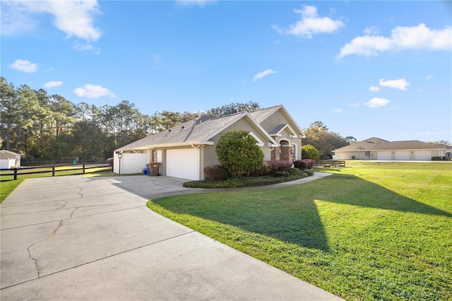 view of side of property with stucco siding, fence, a yard, concrete driveway, and an attached garage