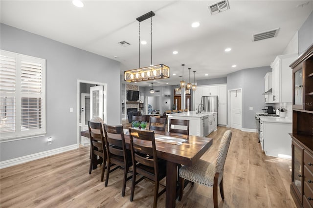 dining area with light wood-style flooring, recessed lighting, a fireplace, and visible vents