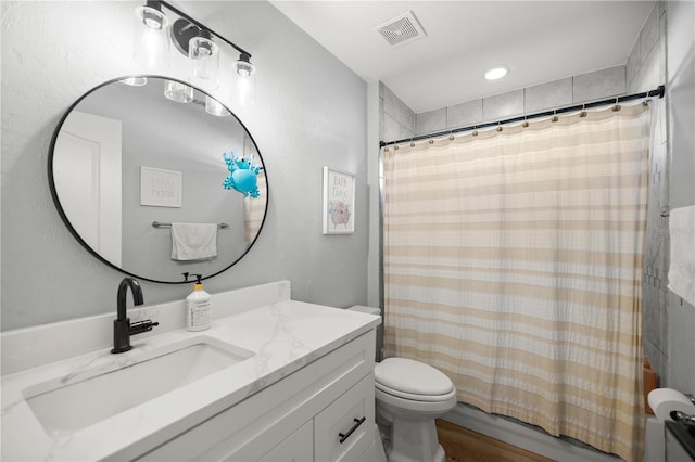 bathroom with visible vents, shower / bath combo with shower curtain, toilet, wood finished floors, and vanity