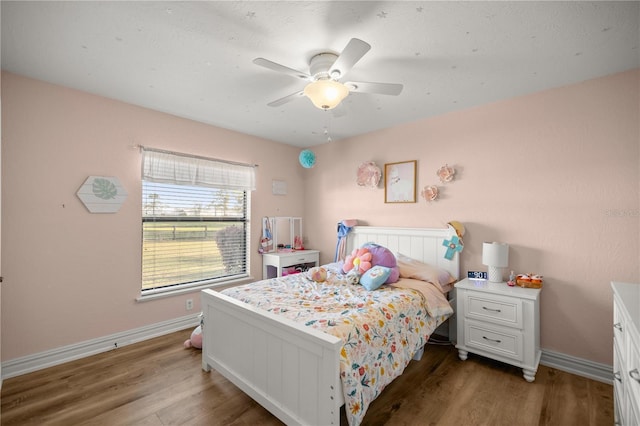 bedroom with ceiling fan, baseboards, and wood finished floors