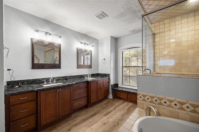 bathroom with visible vents, a stall shower, a sink, a textured ceiling, and wood finished floors