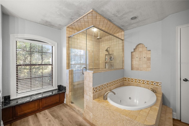 full bathroom featuring a stall shower, a jetted tub, a textured ceiling, and wood finished floors