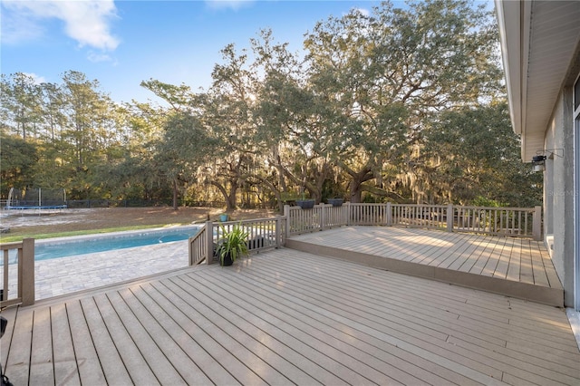 wooden terrace with an outdoor pool and a trampoline