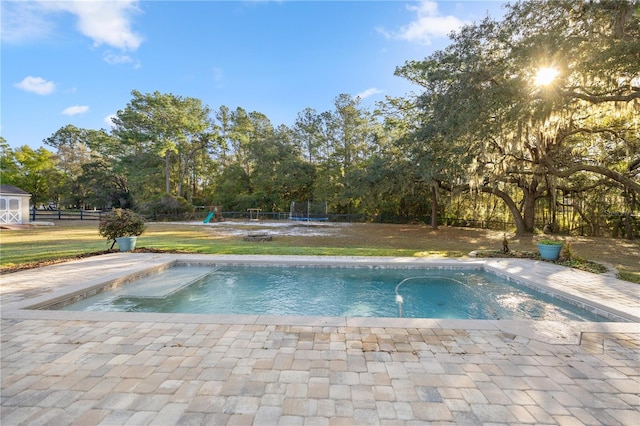 view of swimming pool featuring a yard, a playground, a trampoline, and fence