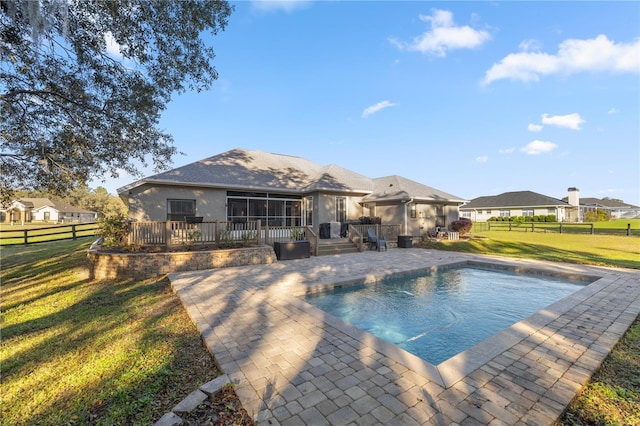 outdoor pool with a patio, a lawn, fence private yard, and a sunroom