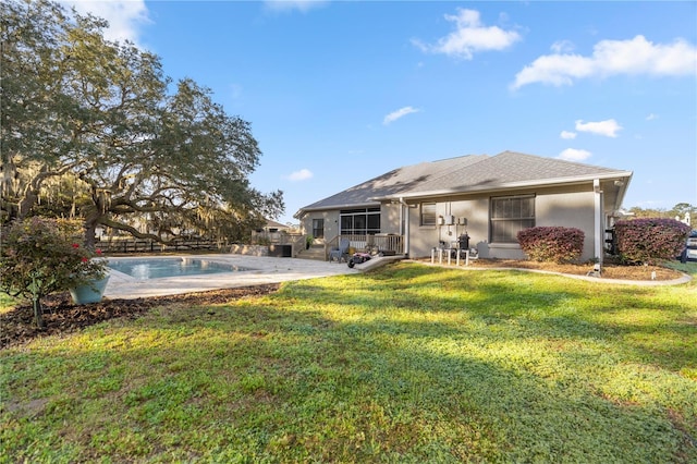 rear view of house featuring fence, an outdoor pool, stucco siding, a patio area, and a lawn