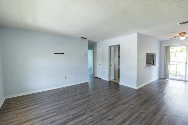 empty room with dark wood finished floors, baseboards, visible vents, and a textured ceiling