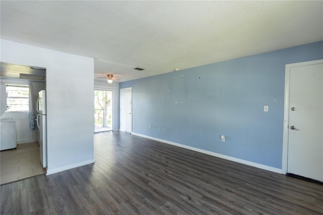 empty room featuring dark wood-type flooring, visible vents, baseboards, and a textured ceiling