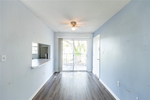 empty room featuring ceiling fan, baseboards, a textured ceiling, and dark wood-style floors