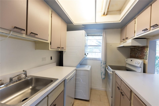 kitchen featuring a sink, under cabinet range hood, stacked washing maching and dryer, white appliances, and light countertops