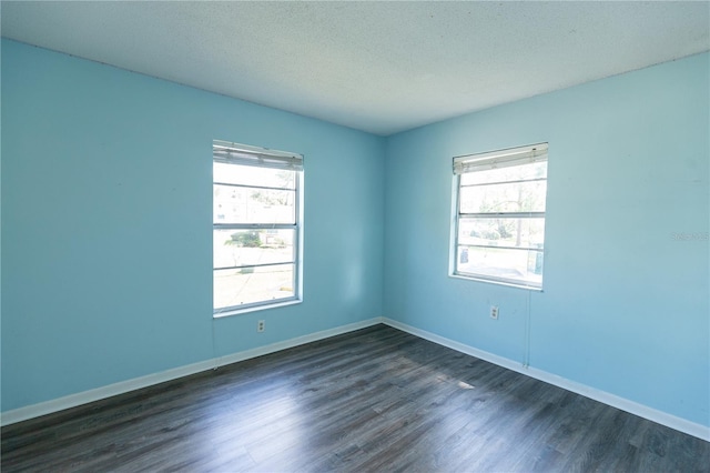 unfurnished room featuring baseboards, dark wood-type flooring, and a textured ceiling