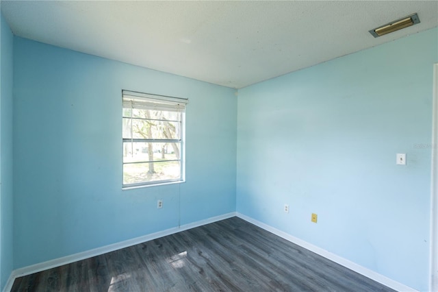 spare room featuring dark wood finished floors, baseboards, and visible vents