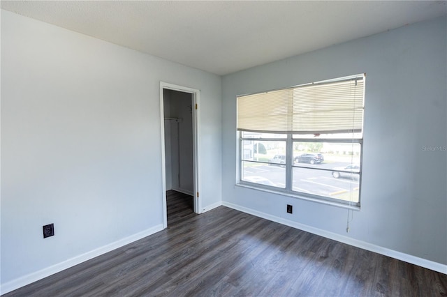 empty room featuring dark wood-type flooring and baseboards