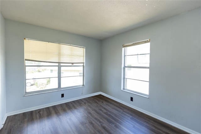 empty room featuring a textured ceiling, baseboards, and dark wood-style flooring