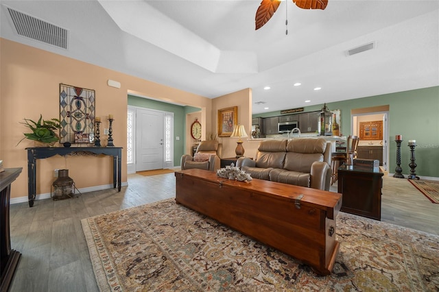 living area featuring wood finished floors, a ceiling fan, and visible vents