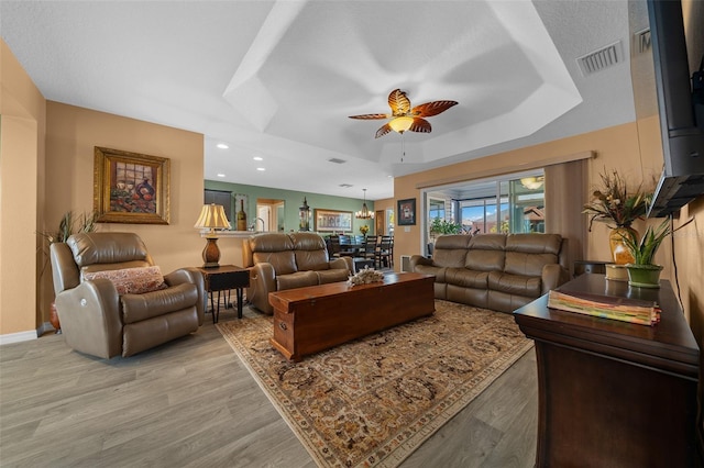 living room featuring visible vents, ceiling fan, recessed lighting, light wood-style flooring, and a raised ceiling