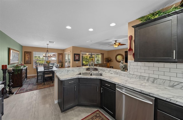 kitchen with a peninsula, light wood-style flooring, a sink, decorative backsplash, and stainless steel dishwasher