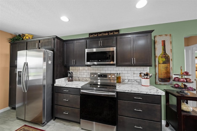 kitchen with backsplash, baseboards, appliances with stainless steel finishes, and dark brown cabinets