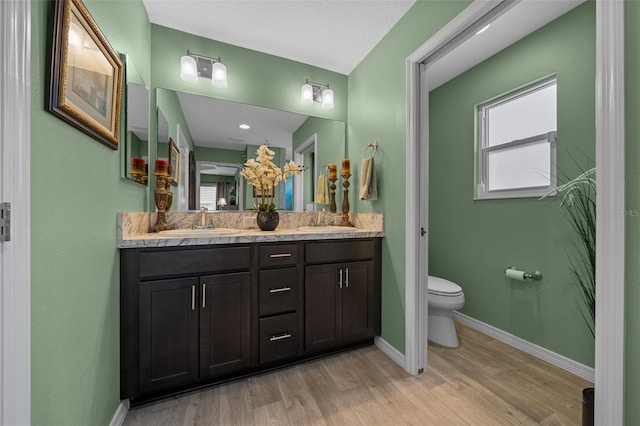 bathroom with a sink, baseboards, toilet, and wood finished floors