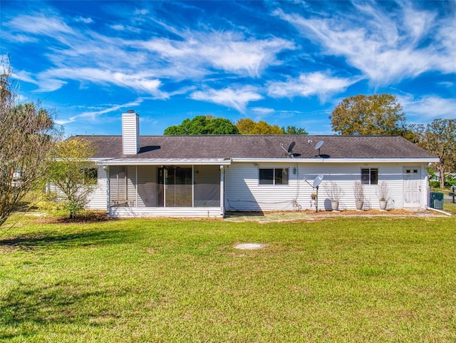 back of property featuring a shingled roof, a chimney, a yard, and a sunroom