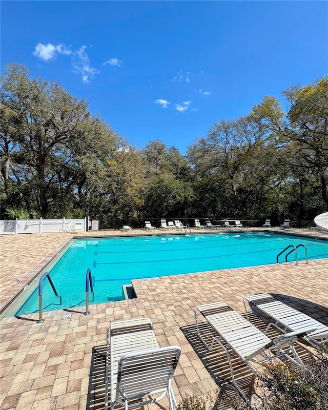 pool with a patio area and fence