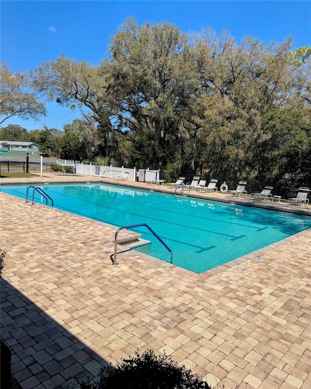 pool with a patio area and fence