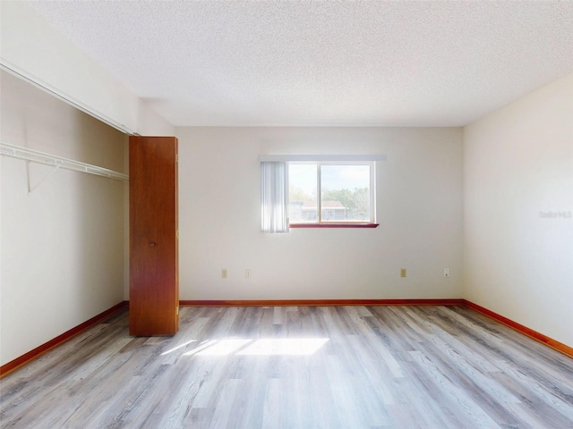 11197 SW 79th Ave, Ocala, FL 34476 - unfurnished bedroom featuring light wood-style flooring, a textured ceiling, a closet, and baseboards
