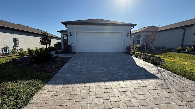 view of front of home featuring decorative driveway, a garage, and stucco siding