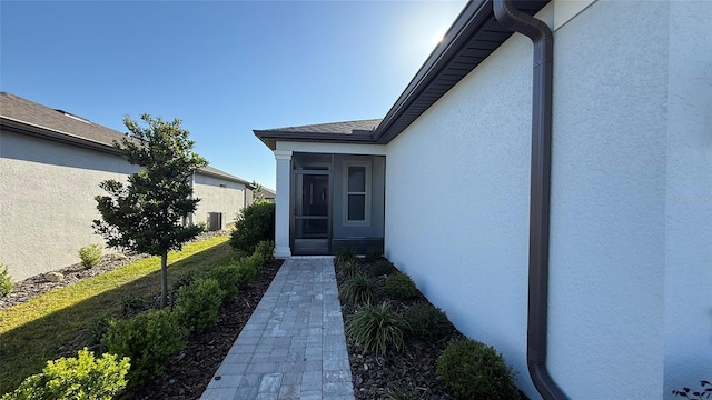 property entrance featuring central air condition unit and stucco siding