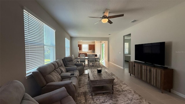 living room with visible vents, a textured ceiling, light tile patterned flooring, baseboards, and ceiling fan