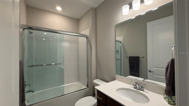 bathroom with combined bath / shower with glass door, toilet, and vanity