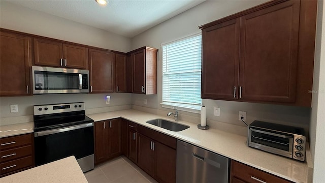 kitchen with a toaster, light countertops, light tile patterned floors, stainless steel appliances, and a sink