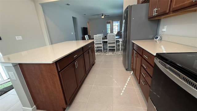 kitchen with light tile patterned floors, electric range, a kitchen island, and light countertops