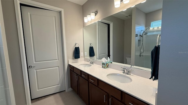 bathroom featuring a tile shower, tile patterned flooring, toilet, and a sink