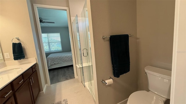 bathroom with an enclosed shower, toilet, vanity, and tile patterned flooring