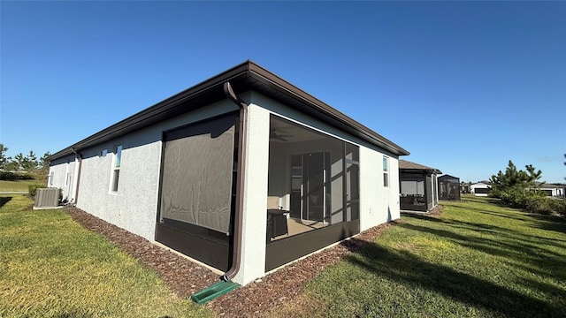 view of property exterior with a yard, stucco siding, central AC, and a sunroom