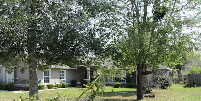 view of front facade featuring stucco siding, fence, a front yard, and a sunroom