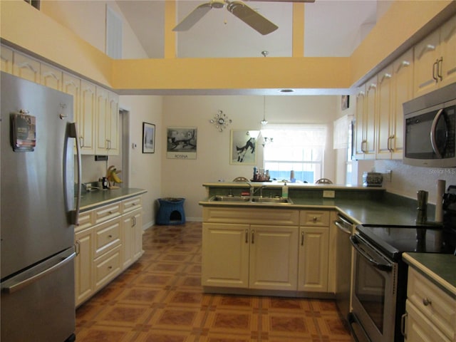 kitchen featuring visible vents, a peninsula, stainless steel appliances, a ceiling fan, and a sink