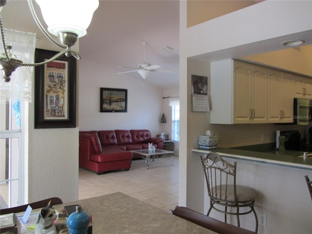 kitchen featuring stainless steel microwave, ceiling fan, open floor plan, lofted ceiling, and light tile patterned floors