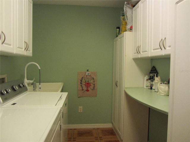 clothes washing area with washing machine and clothes dryer, a sink, baseboards, cabinet space, and dark tile patterned flooring