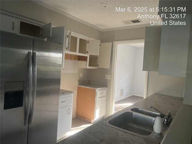 kitchen featuring a sink, visible vents, a textured ceiling, and stainless steel refrigerator with ice dispenser