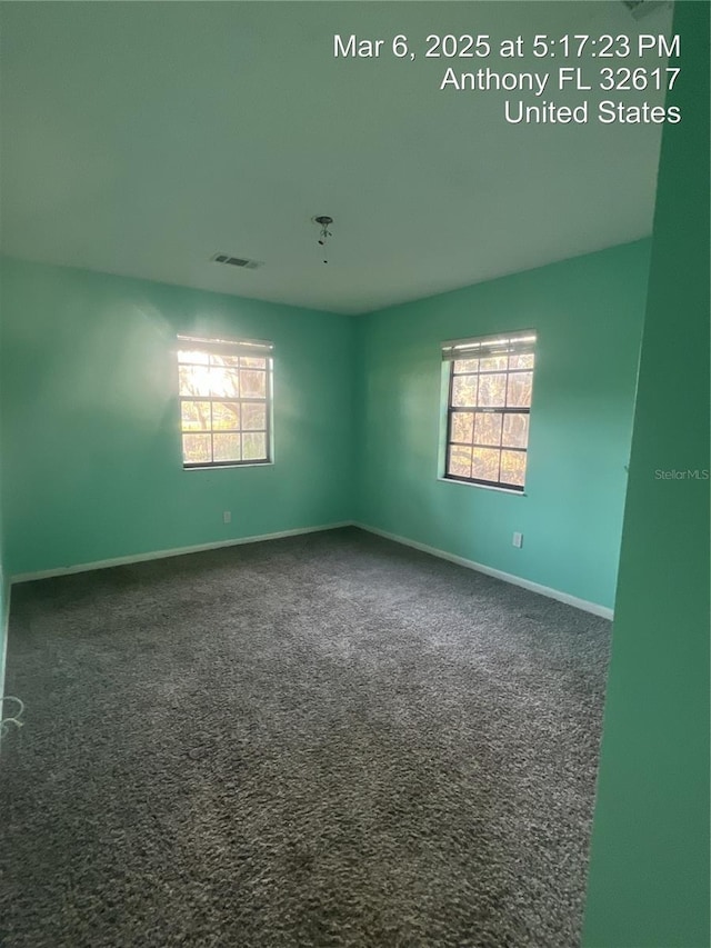 unfurnished room with carpet flooring, baseboards, visible vents, and a wealth of natural light