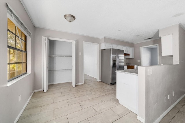 9951 NE 30th Ct, Anthony, FL 32617 - kitchen with white cabinets, visible vents, light countertops, stainless steel fridge, and a peninsula