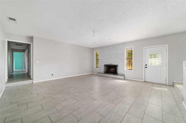 9951 NE 30th Ct, Anthony, FL 32617 - unfurnished living room with a large fireplace, a textured ceiling, baseboards, and visible vents