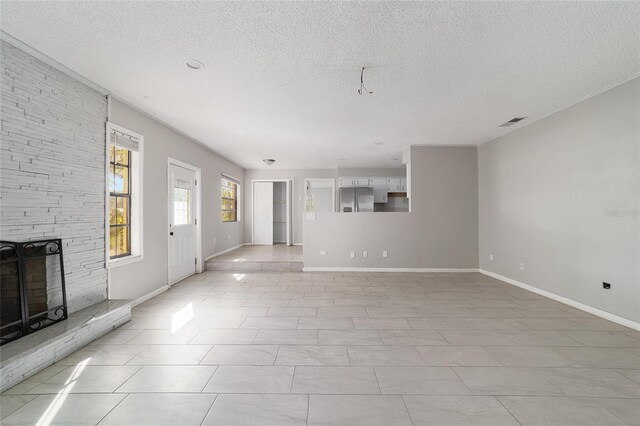 9951 NE 30th Ct, Anthony, FL 32617 - unfurnished living room featuring baseboards, a textured ceiling, visible vents, and a stone fireplace
