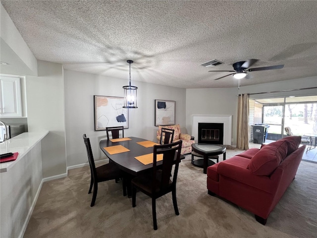 dining room featuring visible vents, ceiling fan, baseboards, carpet floors, and a glass covered fireplace