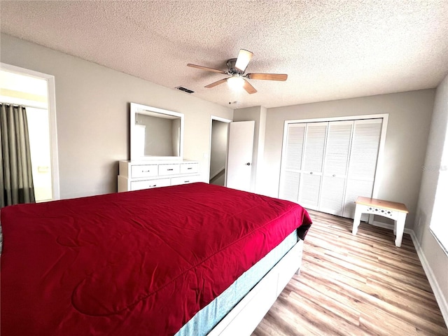 bedroom featuring light wood-type flooring, visible vents, a ceiling fan, a textured ceiling, and a closet