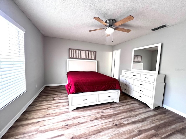 unfurnished bedroom featuring visible vents, baseboards, a textured ceiling, and wood finished floors