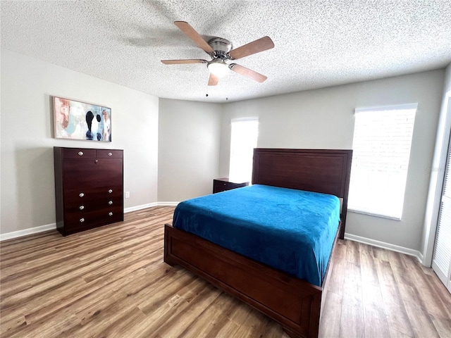 bedroom with ceiling fan, a textured ceiling, baseboards, and wood finished floors