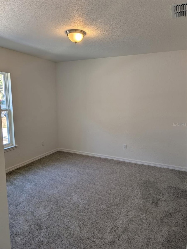 unfurnished room featuring visible vents, carpet floors, a textured ceiling, and baseboards